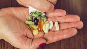 egy nő étrendkiegészítő kapszulákat szór a tenyerébe