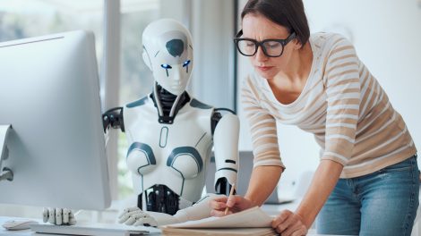 Nő és mesterséges intelligencia robot dolgozik együtt az irodában