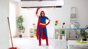 szupernő ruhába öltözött nő takarít és felemeli a kanapét