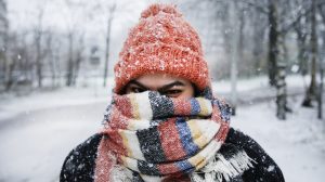 fiatal nő mosolyog a hóesésben sapkában és sálban