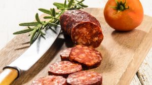 felszeletelt kolbász vágódeszkán paradicsommal