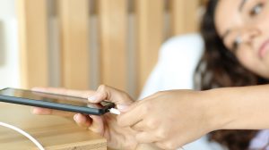 nő mobiltelefont tölt éjszaka az ágya mellett