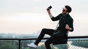 mobiltelefonról zenét hallgat egy fiatal férfi