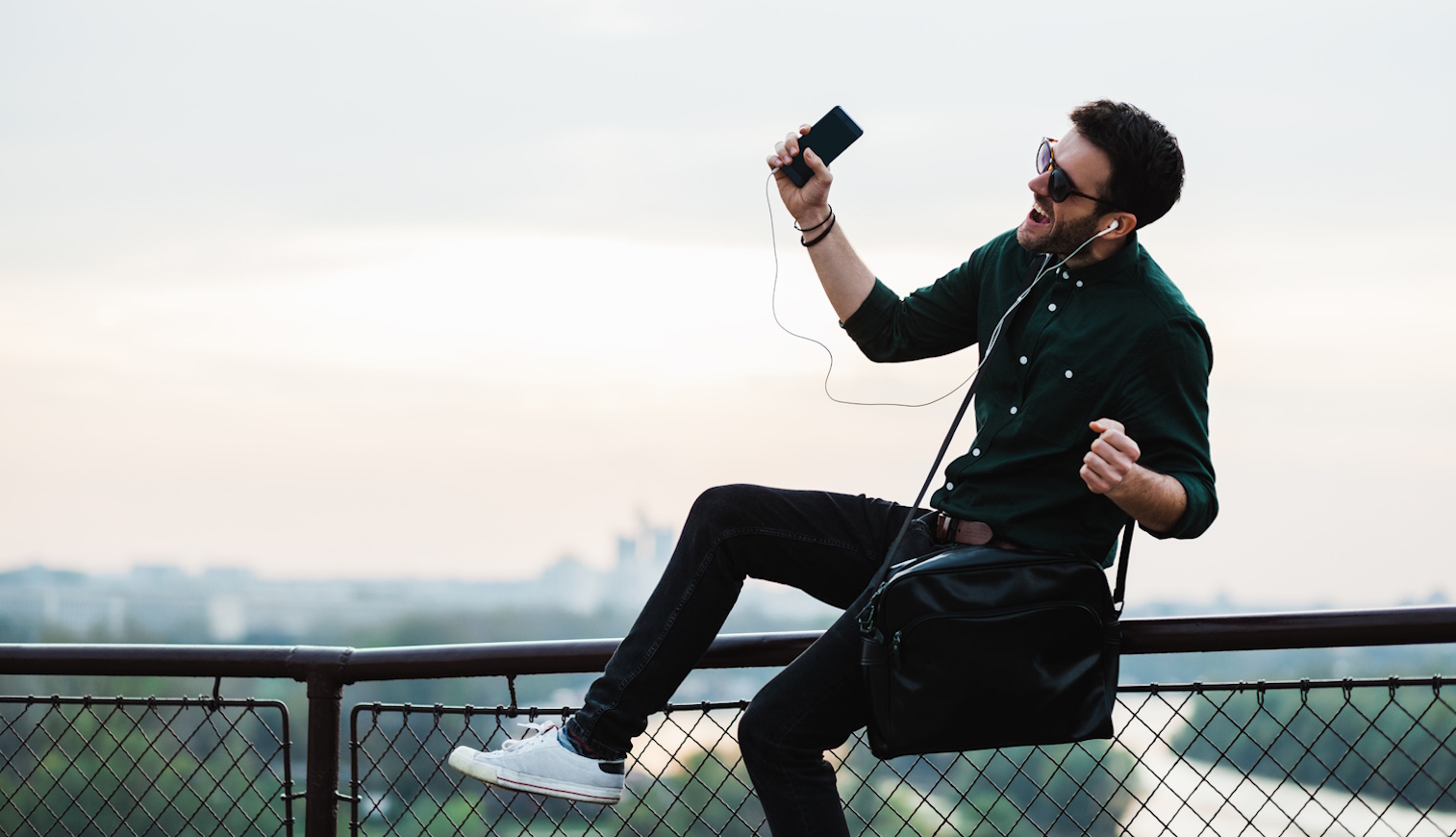mobiltelefonról zenét hallgat egy fiatal férfi
