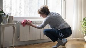 idős nő a radiátort takarítja