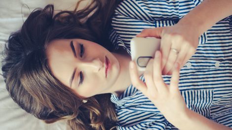nő az ágyban a telefonját nyomkodja