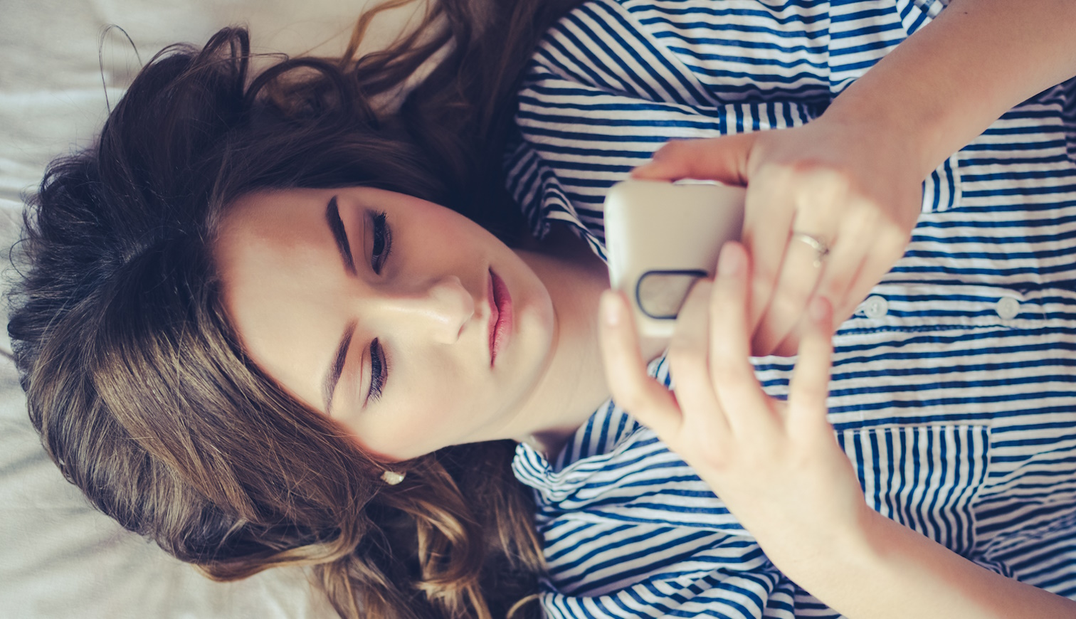 nő az ágyban a telefonját nyomkodja