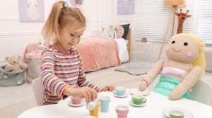 kislány teapartit játszik babával az asztalnál
