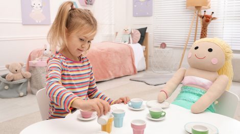 kislány teapartit játszik babával az asztalnál