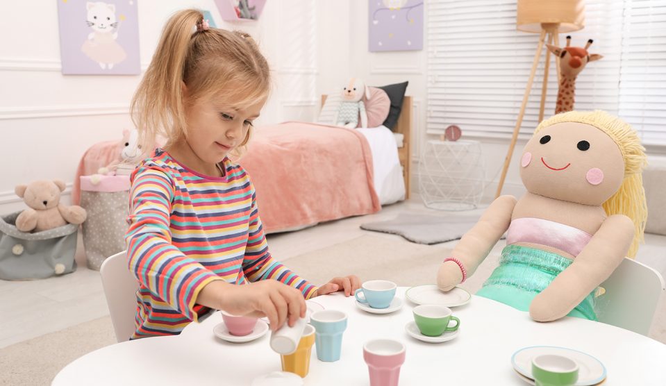 kislány teapartit játszik babával az asztalnál