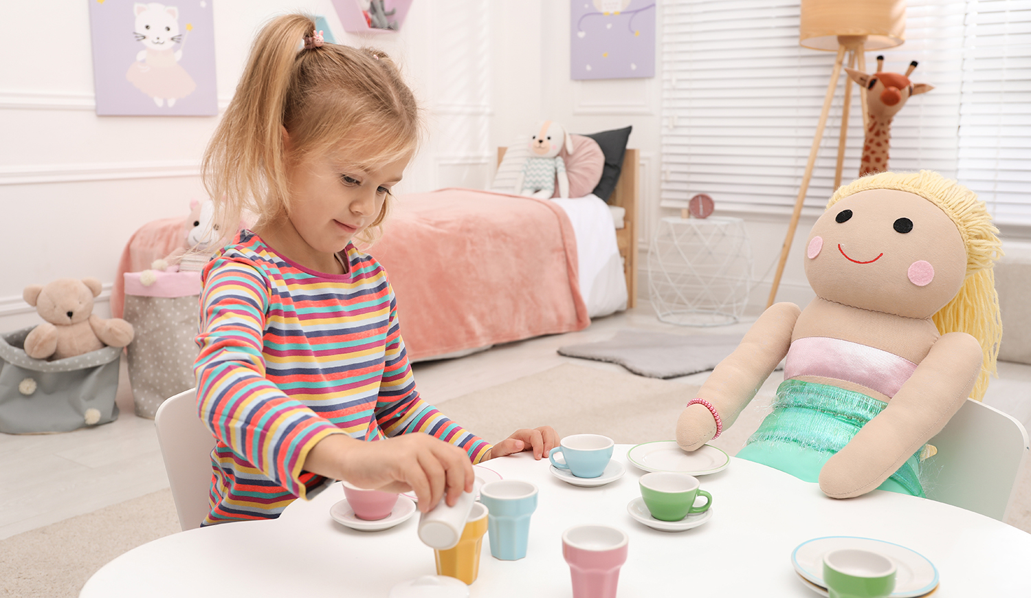 kislány teapartit játszik babával az asztalnál