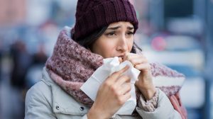 Egy lány zsebkendőben köhög az utcán