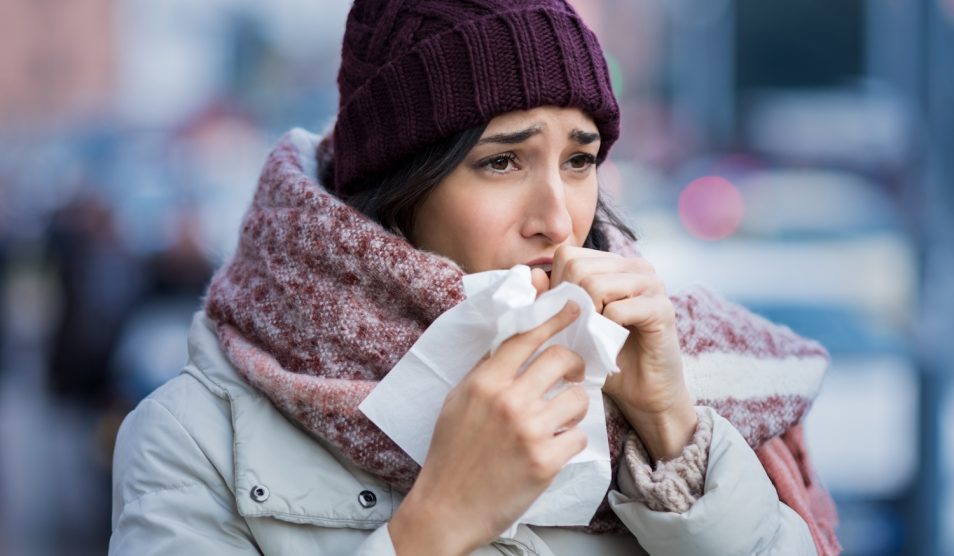 Egy lány zsebkendőben köhög az utcán