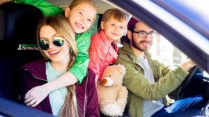 mosolygó család ül az autóban