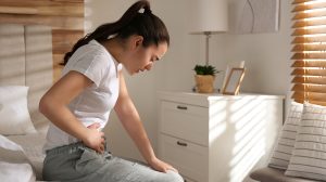 Fiatal nő gyomorfájástól szenved az ágyban