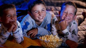 gyerekek mosolyogva nézik a filmet, popcornnal