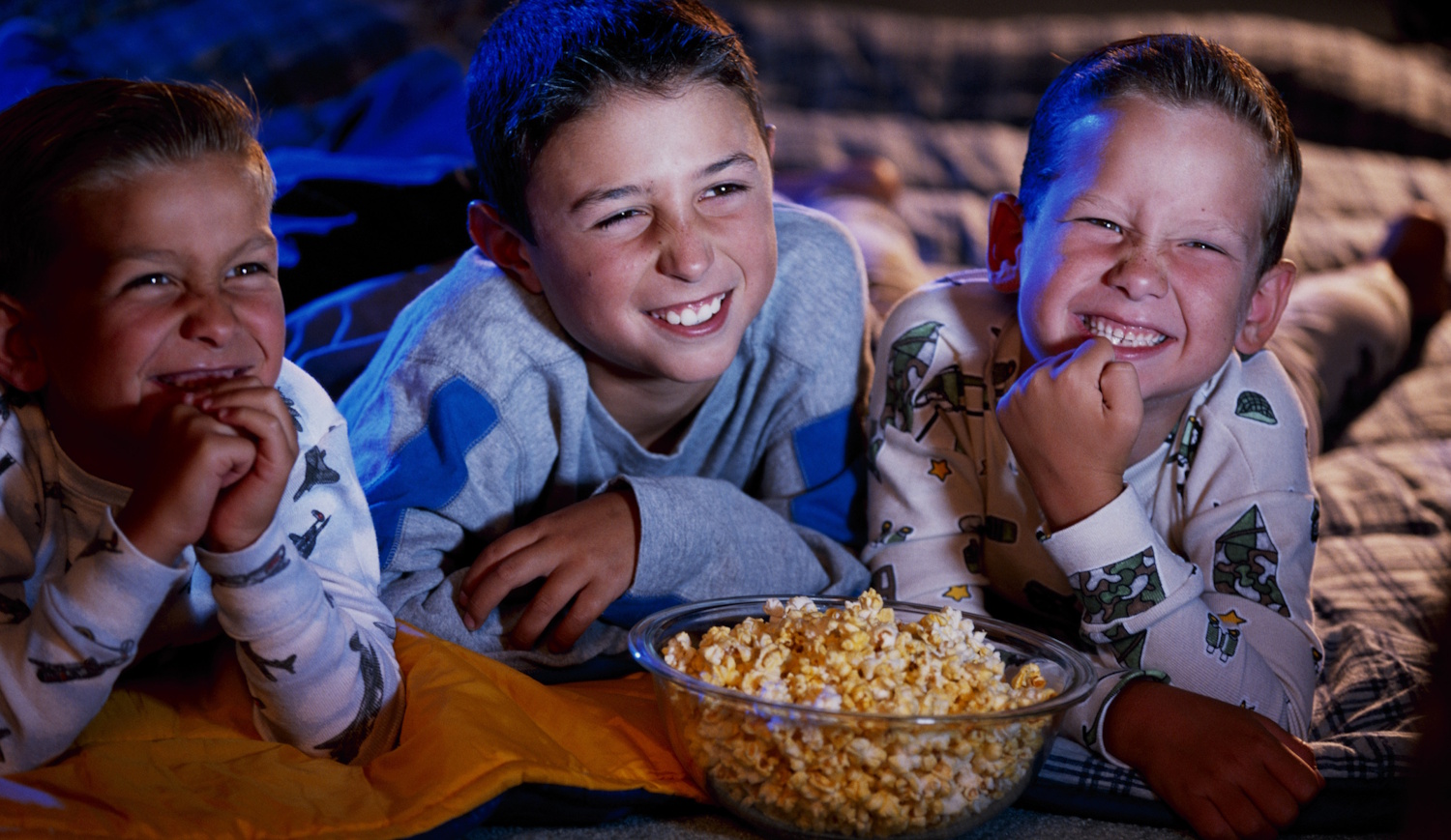 gyerekek mosolyogva nézik a filmet, popcornnal