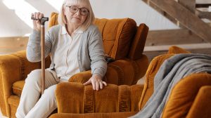 idős nő, sétapálcával a kezében, és a mellette lévő üres helyre néz, miközben a férjét gyászolja