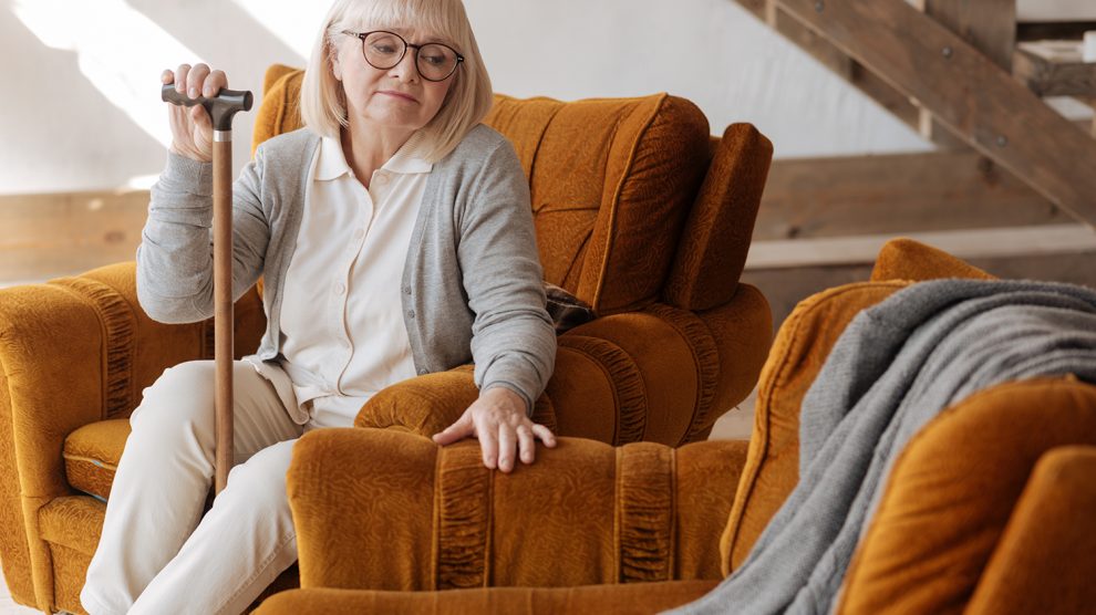 idős nő, sétapálcával a kezében, és a mellette lévő üres helyre néz, miközben a férjét gyászolja