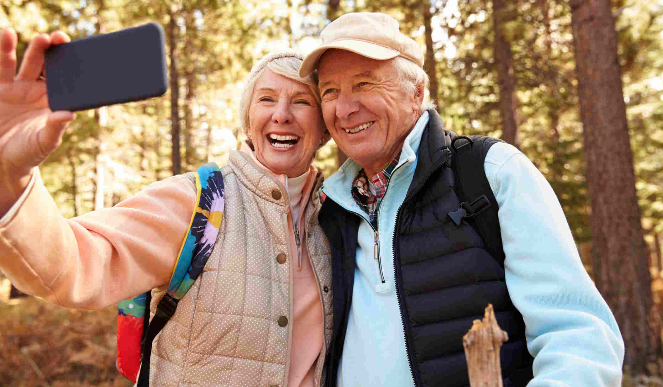 idős házaspár ősszel kirándul miközben fotózzák magukat