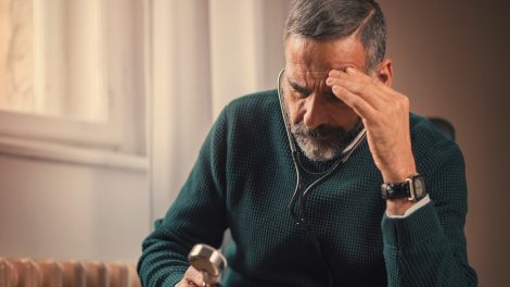 idős férfi gondterhelten nézi a fonendoszkópot