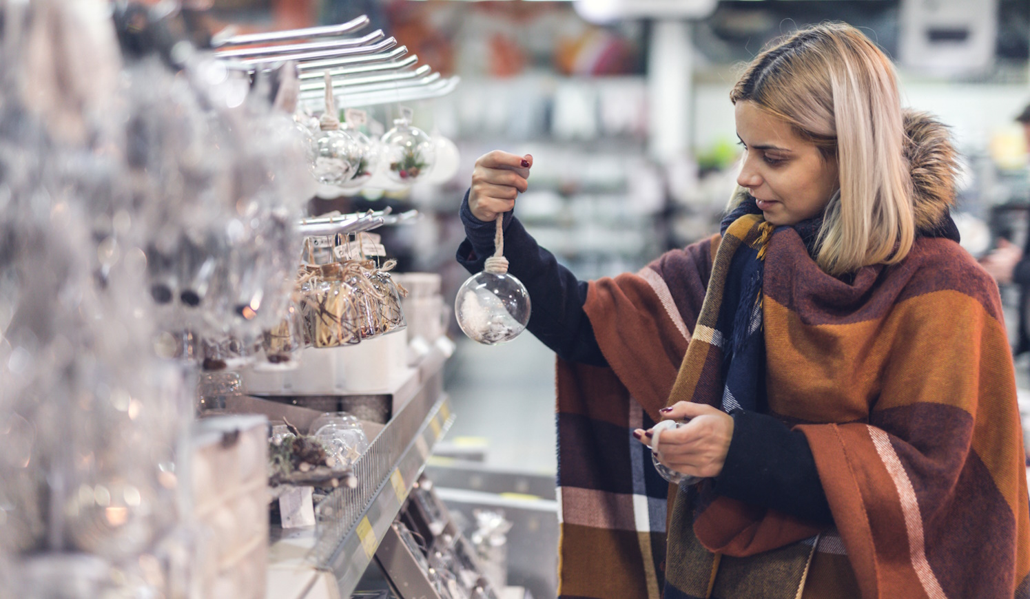 karácsonyi dekoráció között válogat egy nő a boltban