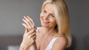 középkorú nő hidratáló krémet ken a kezére