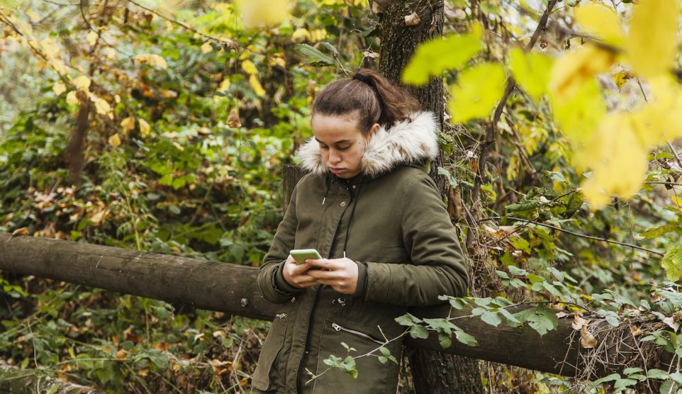 tinédzser lány az erőben a telefonját nyomkodja