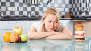 Egy nő választ édesség és gyümölcs közül a konyhában