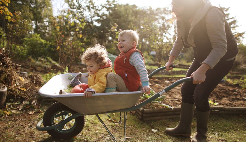 anyuka két kisgyerekével játszik ősszel a kertben