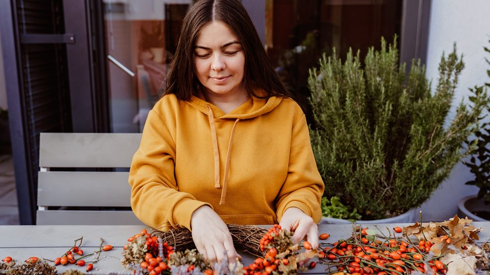 Lány virágos őszi ajtókoszorút készít