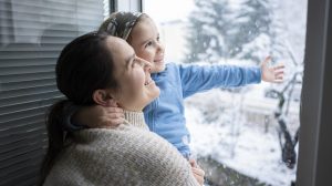 szellőzetés télen anya és kislánya állnak mosolyogva a nyitott ablaknál
