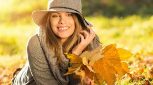 Boldog fiatal nő levelekkel a parkban ősszel