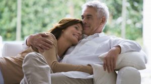 középkorú szerelmespár egymáshoz bújik a kanapén