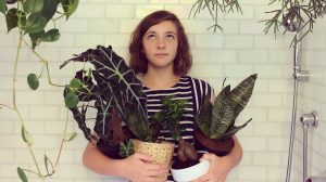 lány a zuhanyzóban áll szobanövényekkel a kezében