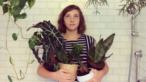 lány a zuhanyzóban áll szobanövényekkel a kezében