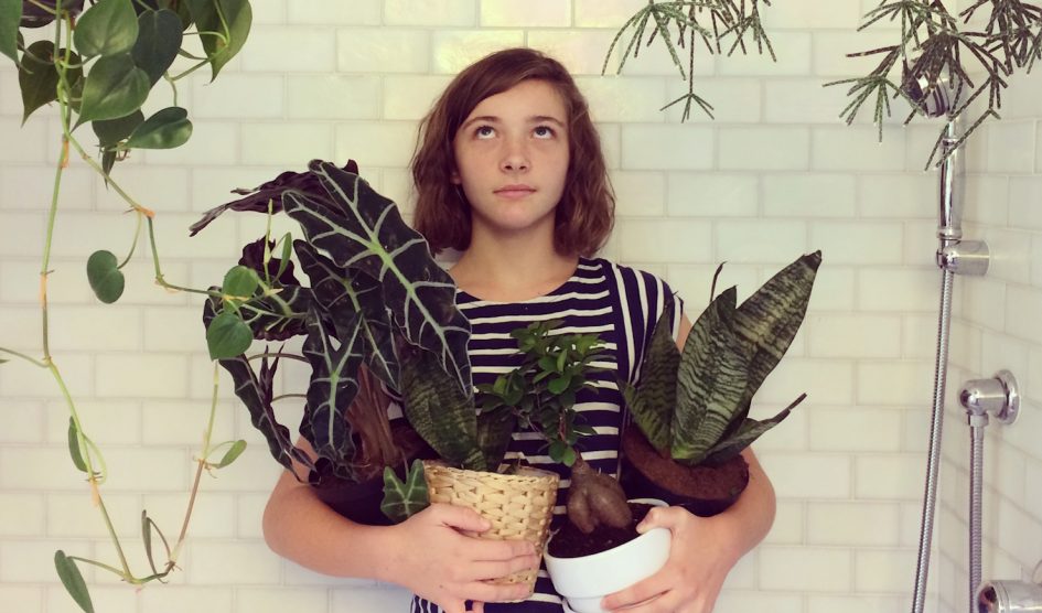 lány a zuhanyzóban áll szobanövényekkel a kezében