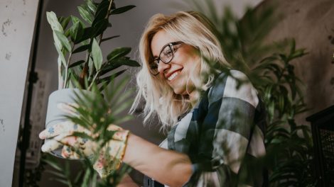 boldog fiatal nő örül a szobanövényeinek