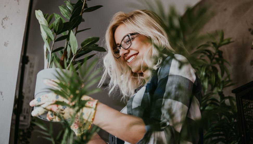 boldog fiatal nő örül a szobanövényeinek