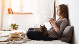 nő az ágyban teázik macskával