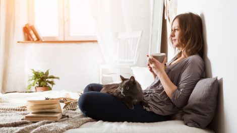 nő az ágyban teázik macskával