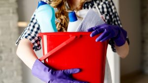 Egy nő tisztítószereket tartba kezében