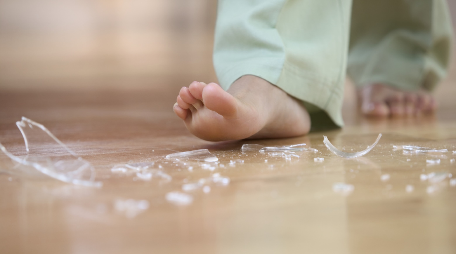 üvegszilánkok felé közelít a meztelen talpával egy nő