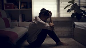 Egy nő elkeseredve ül a sötét szobában