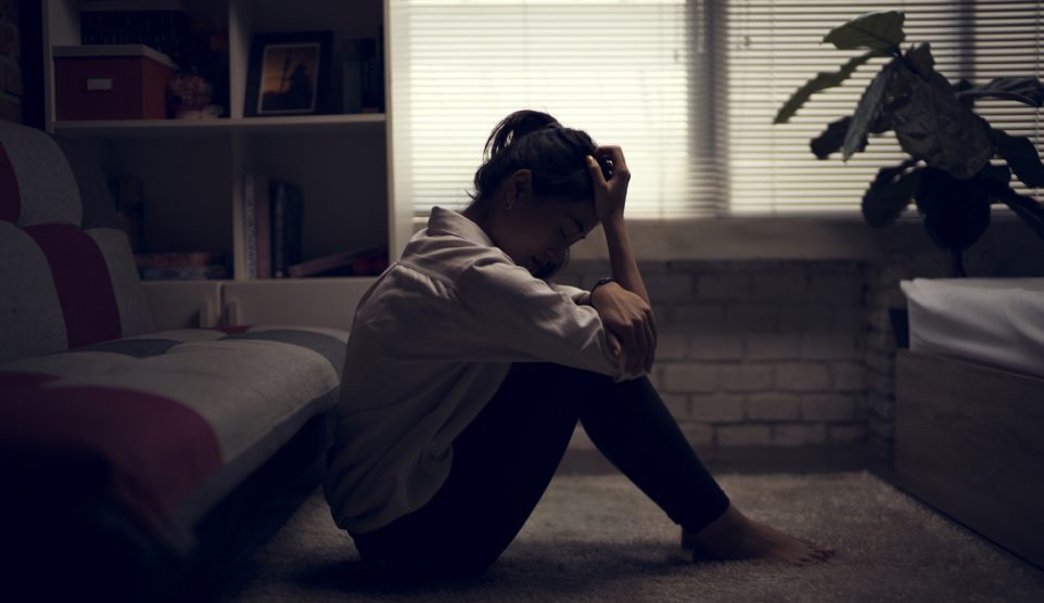 Egy nő elkeseredve ül a sötét szobában