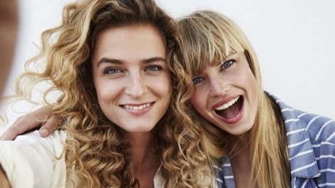 Két fiatal nő ölelkezve mosolyognak