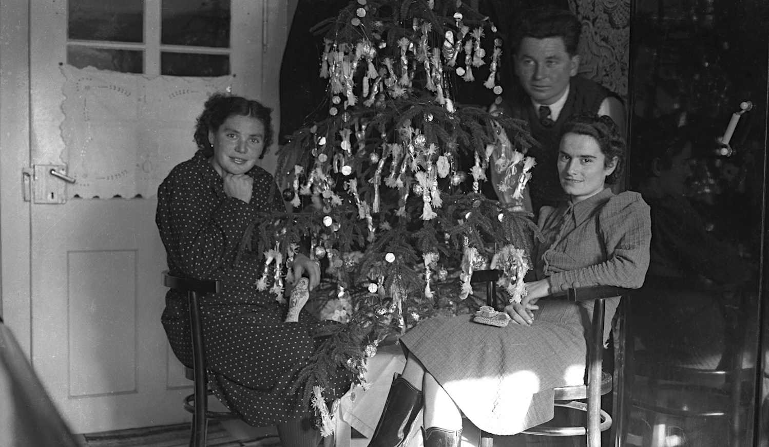 régi retró karácsonyfa előtt ülnek emberek