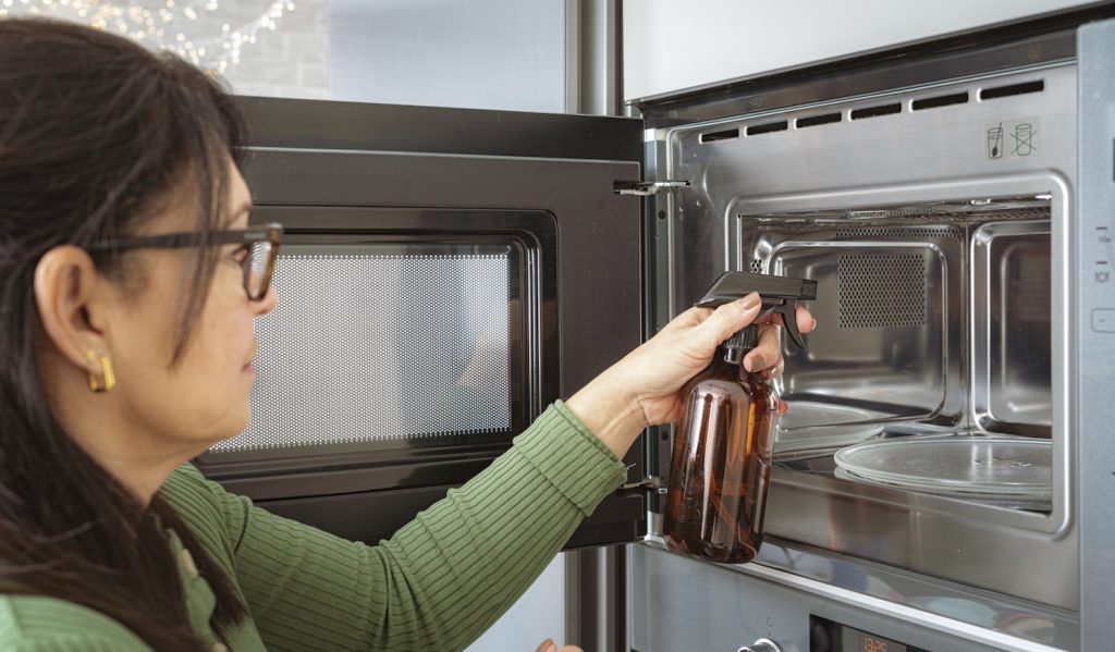 nő ecettel takarítja a mikrót