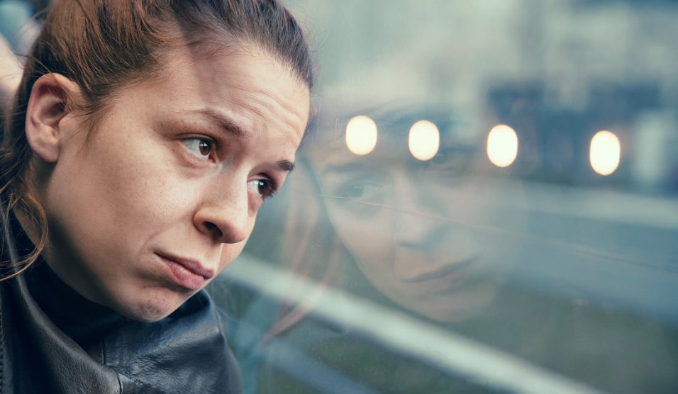 Egy nő fáradtan néz ki az ablakon