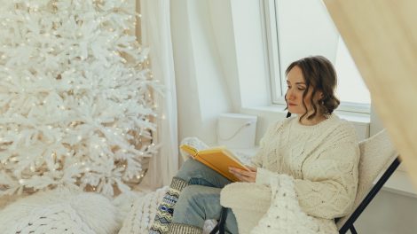 hófehér függönyök előtt ül a karácsonyfánál nő karácsonykor